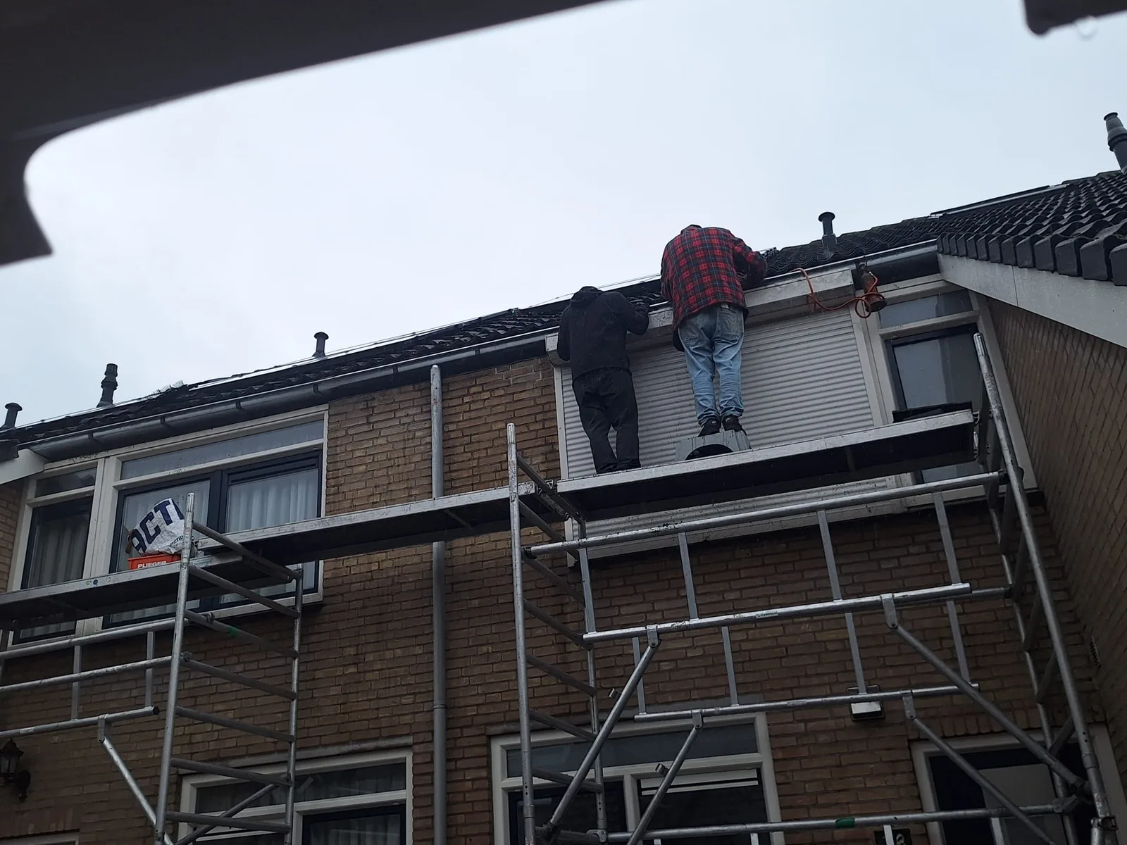 Werk aan de dakrand en goot vanaf een steiger