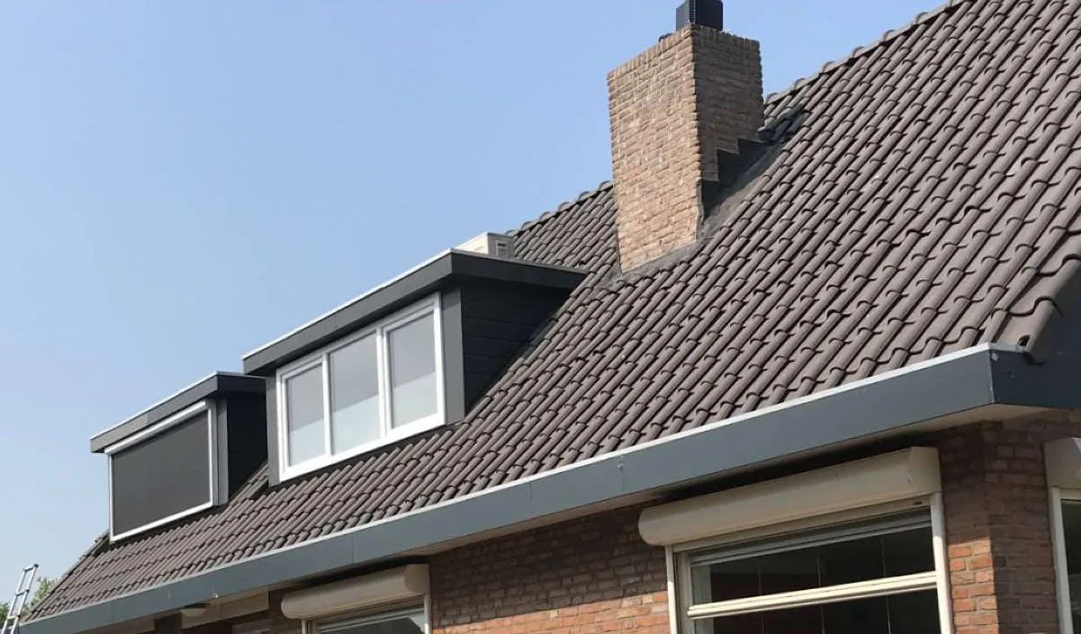 Afgewerkt hellend pannendak met dakkapel onder een blauwe lucht